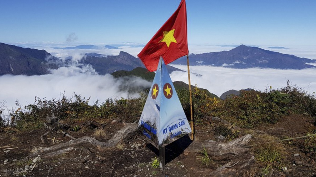 Cột mốc đỉnh Kỳ Quan San cùng lá cờ đỏ sao vàng giữa biển mây và núi