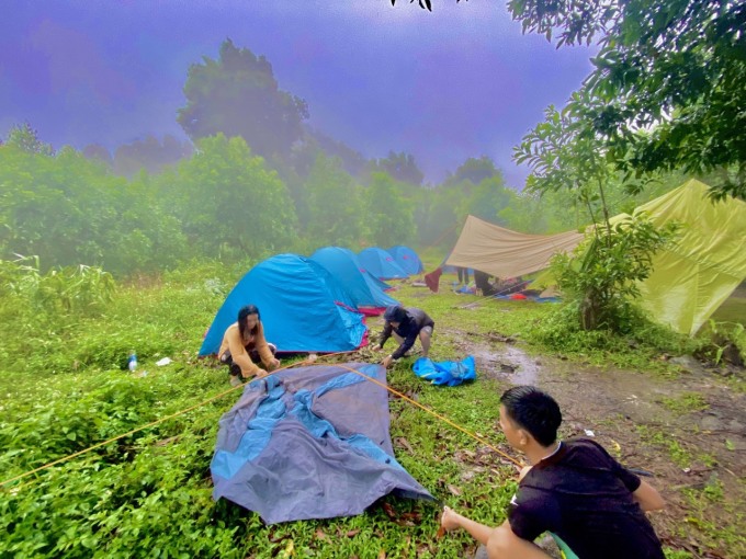 Phương Linh (áo vàng), cùng mọi người dựng lều trong cơn mưa. Ảnh: NVCC